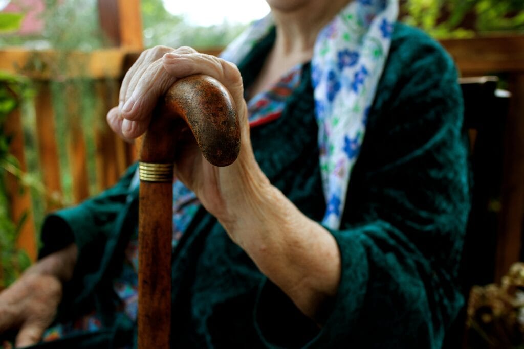 Senior adult holding a wooden cane, symbolizing strength and support.