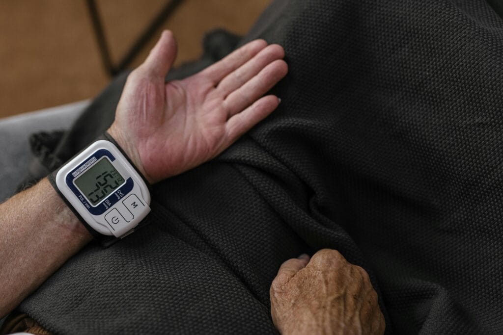 A senior adult using a wrist blood pressure monitor at home, focusing on health screening.